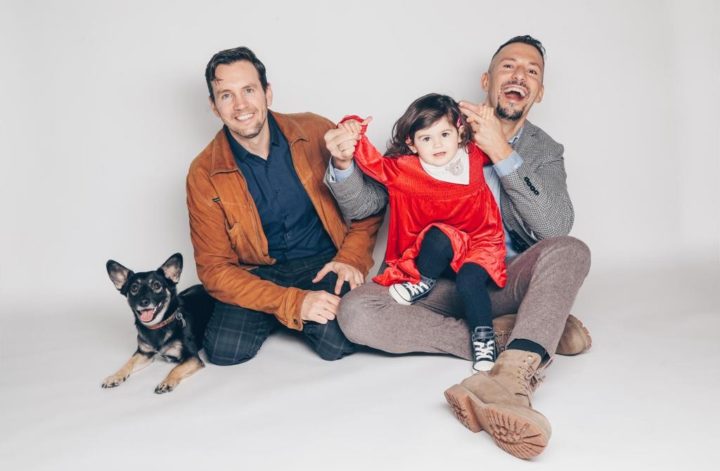 A heartfelt moment showing a gay couple sharing love and joy while lifting and embracing a child.