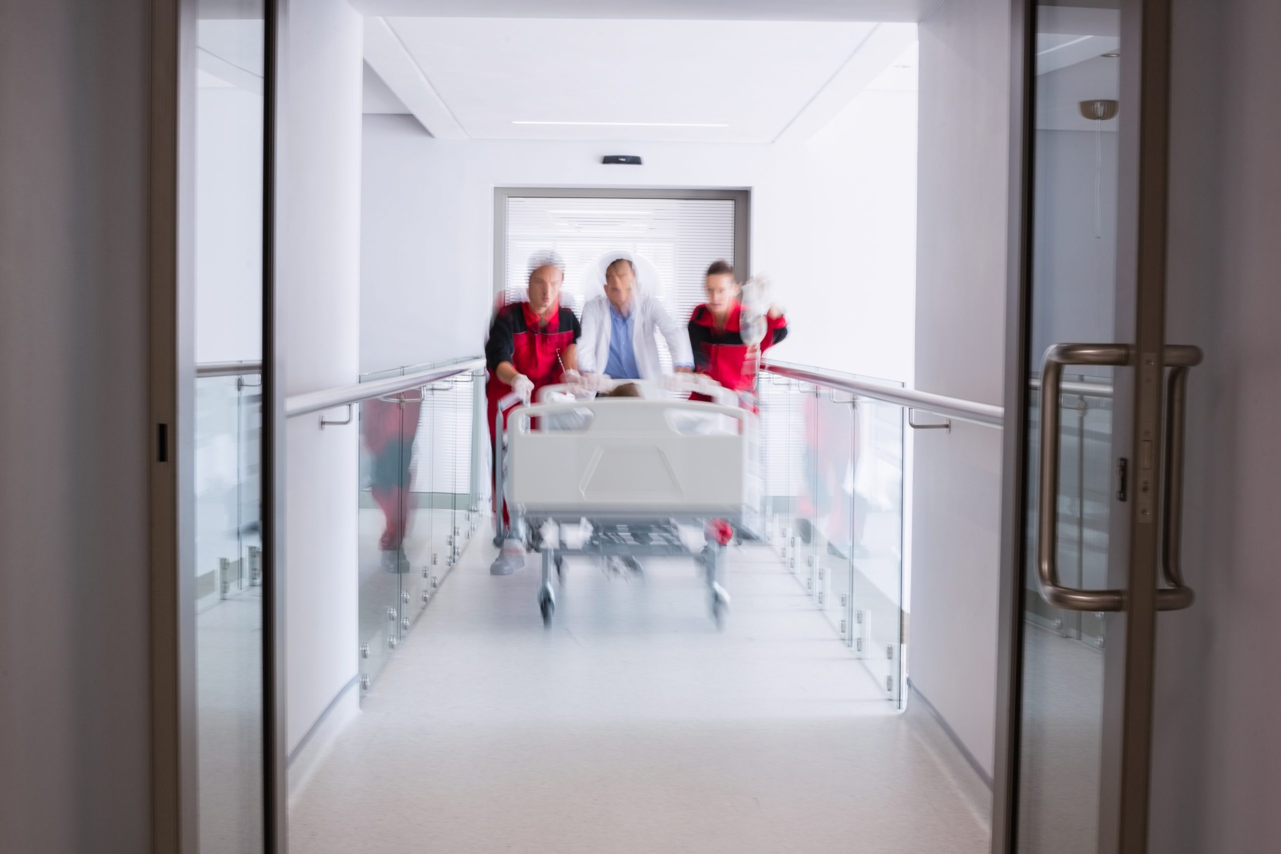 doctors pushing emergency stretcher bed corridor 300x200 1